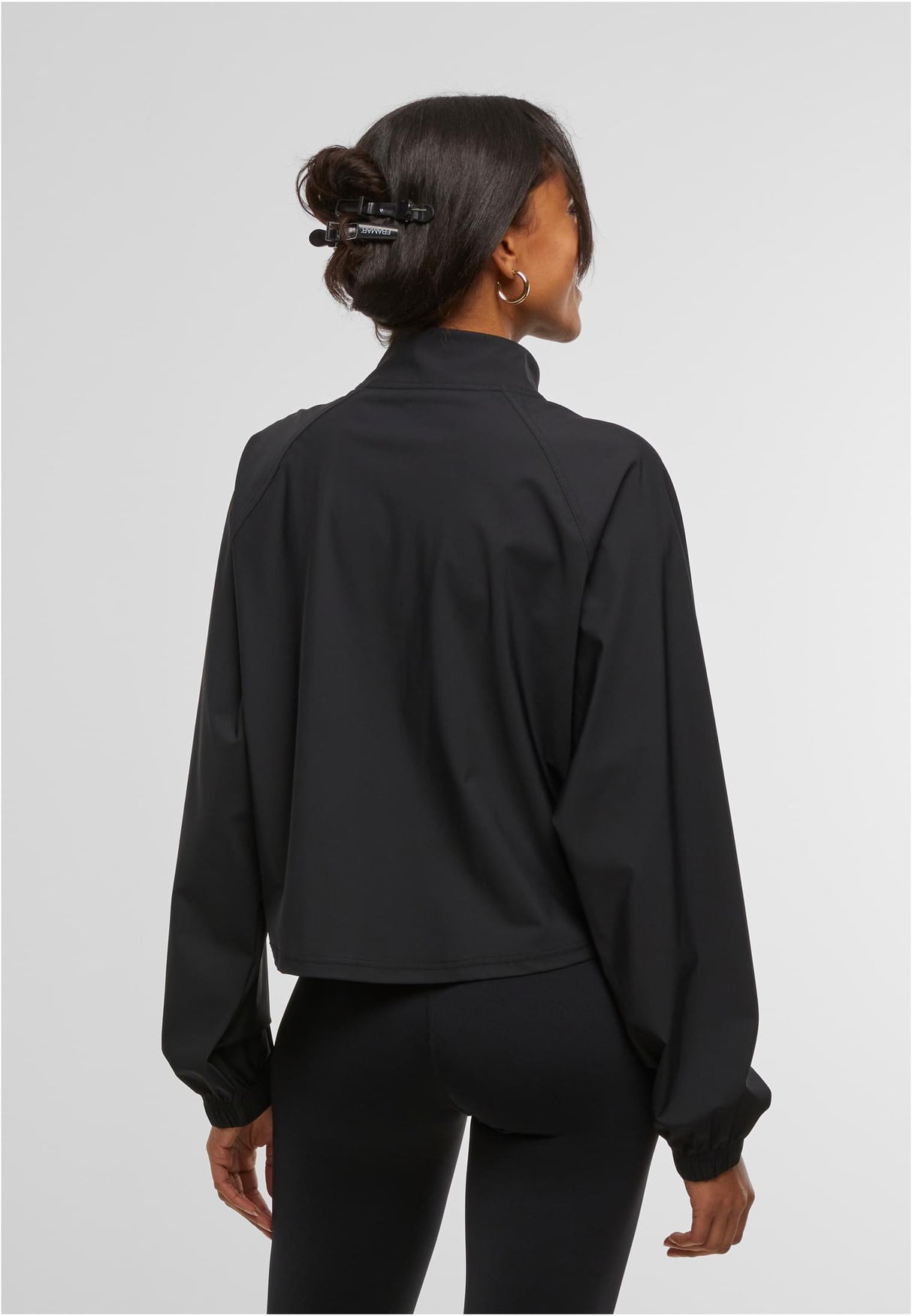 En kvinna visar baksidan av den svarta sportjackan UC Sports Jacket.