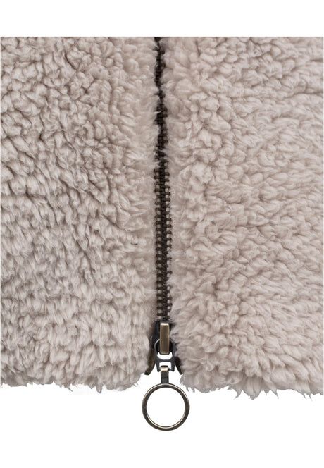 Närbild på den beige UC Sherpa Jackans mjuka sherpa-tyg och dragkedja med ring.