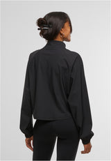 En kvinna visar baksidan av den svarta sportjackan UC Sports Jacket.